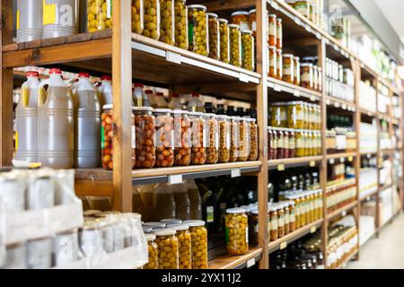 Bocaux en verre avec diverses olives marinées affichées sur les étagères du magasin Banque D'Images