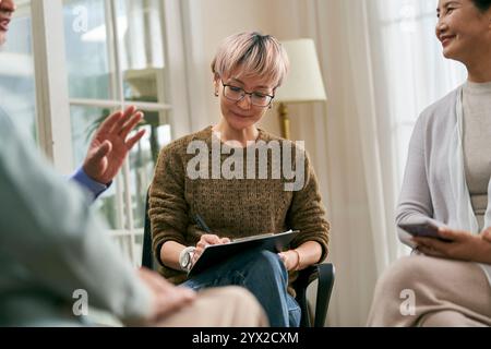 conseillère féminine asiatique dirigeant une séance de discussion pour un groupe de personnes âgées Banque D'Images