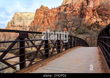 Un pont sur une rivière avec vue sur les montagnes en arrière-plan. Le pont est en métal et a une passerelle en bois Banque D'Images