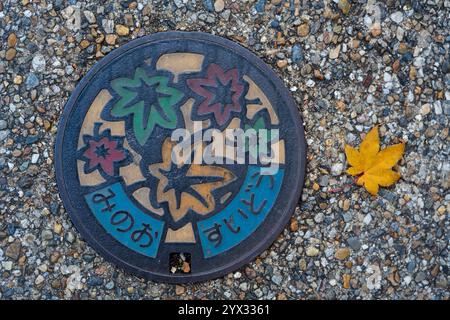 Un design coloré de couvercle de trou d'homme avec des feuilles d'érable d'automne dans la ville de Minoh, Osaka, Japon. Traduction : approvisionnement en eau de la ville de Minoh. Banque D'Images