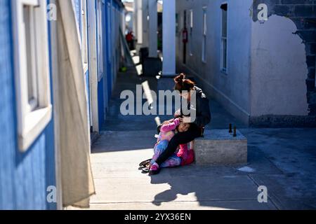 Reynosa, Mexique. 11 décembre 2024. Une migrante fixe les cheveux d'une jeune fille dans un refuge de la ville frontalière de Reynosa, Tamaulipas, Mexique, 11 décembre 2024. Reynosa, une ville frontalière de Tamaulipas, se trouve de l'autre côté du Rio Grande de McAllen, Texas des États-Unis. En raison de sa situation géographique, Reynosa sert de porte d'entrée majeure pour les migrants d'Amérique centrale et d'autres régions qui tentent d'entrer aux États-Unis. Les refuges de cette région fournissent un logement temporaire aux migrants en attente de demandes d'asile, de permis de transit ou de retour dans leur foyer. Crédit : Li Muzi/Xinhua/Alamy Live News Banque D'Images