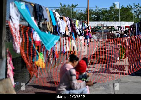 Reynosa, Mexique. 11 décembre 2024. Un migrant pend un tissu dans un refuge de la ville frontalière de Reynosa, Tamaulipas, Mexique, 11 décembre 2024. Reynosa, une ville frontalière de Tamaulipas, se trouve de l'autre côté du Rio Grande de McAllen, Texas des États-Unis. En raison de sa situation géographique, Reynosa sert de porte d'entrée majeure pour les migrants d'Amérique centrale et d'autres régions qui tentent d'entrer aux États-Unis. Les refuges de cette région fournissent un logement temporaire aux migrants en attente de demandes d'asile, de permis de transit ou de retour dans leur foyer. Crédit : Li Muzi/Xinhua/Alamy Live News Banque D'Images