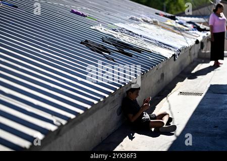 Reynosa, Mexique. 11 décembre 2024. Un garçon joue à des jeux vidéo dans un refuge de la ville frontalière de Reynosa, Tamaulipas, Mexique, 11 décembre 2024. Reynosa, une ville frontalière de Tamaulipas, se trouve de l'autre côté du Rio Grande de McAllen, Texas des États-Unis. En raison de sa situation géographique, Reynosa sert de porte d'entrée majeure pour les migrants d'Amérique centrale et d'autres régions qui tentent d'entrer aux États-Unis. Les refuges de cette région fournissent un logement temporaire aux migrants en attente de demandes d'asile, de permis de transit ou de retour dans leur foyer. Crédit : Li Muzi/Xinhua/Alamy Live News Banque D'Images