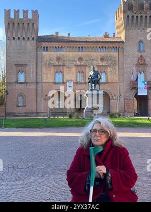 Busseto, Parme, Italie - 23 novembre 2024 touriste tenant une béquille posant sur la piazza giuseppe verdi avec le monument au compositeur et villa Pallav Banque D'Images