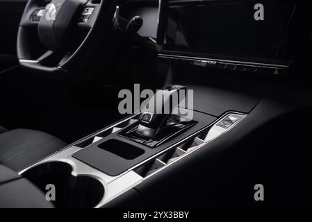 Sélecteur de vitesses automatique et console centrale dans DS7 Crossback. Intérieur de l'automobile dans les tons sombres, vue rapprochée du levier de vitesses, des boutons et des porte-gobelets Banque D'Images