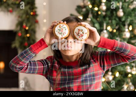 Fille couvrant les yeux avec des biscuits de noël et faisant un visage idiot Banque D'Images