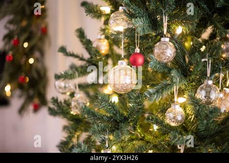 Ornement en or suspendu avec des lumières sur un arbre de noël Banque D'Images