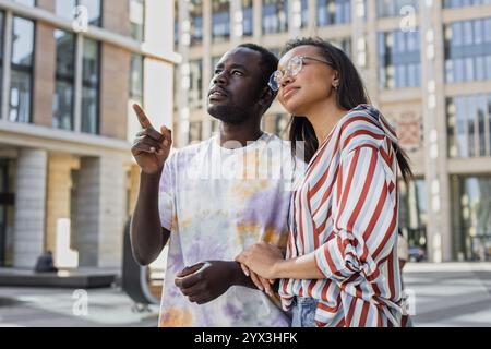 Couple afro-américain et latino marchant le long de la rue urbaine Banque D'Images