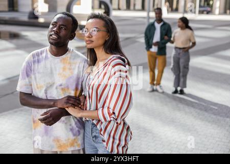 Couple afro-américain et latino marchant le long de la rue urbaine Banque D'Images