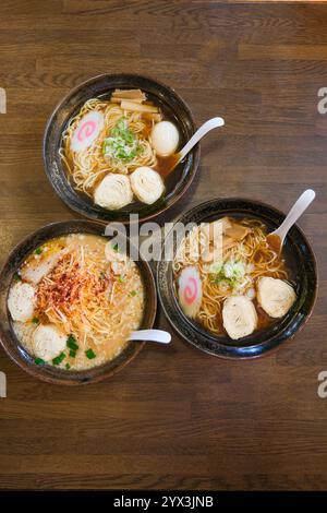 Vue plongeante de trois bols de soupe ramen japonaise assis sur une table. Banque D'Images