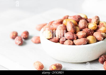 Cacahuète salée grillée sans coquille dans un bol ou un sac en toile de jute sur fond rustique, concept de noix Banque D'Images