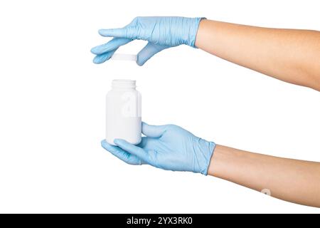 Main dans des gants médicaux tenant un pot blanc avec des comprimés ou des capsules sur un fond vide. Stockage de médicaments, emballage pharmaceutique, soins de santé. Banque D'Images