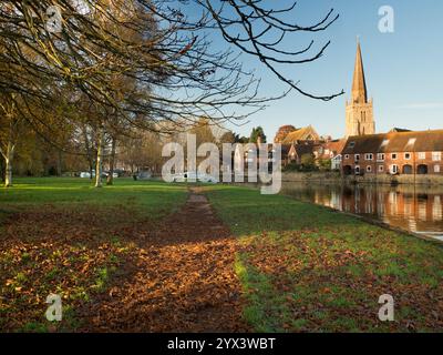 Les feuilles d'automne tombées couvrent la rive nord de la Tamise à Abingdon. Au loin, nous voyons la grande flèche de l'église St Helens, un site de chrétien Banque D'Images