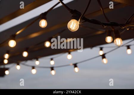 Améliorez vos réunions en plein air avec des jeux de lumières festifs qui créent une ambiance chaleureuse en soirée Banque D'Images