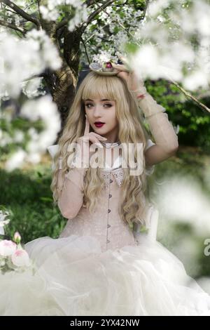 La belle fille avec lapin blanc dans le jardin fleuri de pommiers-arbres. Fleurs blanches dans un jardin ensoleillé. Pommiers de printemps en fleurs. Beaut Banque D'Images