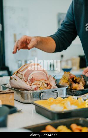 Un homme prépare un grand rôti avec beaucoup de viande dessus. Il assaisonne la viande avec du sel et du poivre Banque D'Images