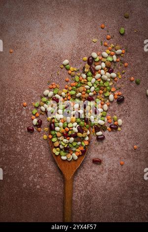 Cuillère en bois, avec un assortiment de légumineuses, haricots, pois, vue de dessus, sur fond brun Banque D'Images