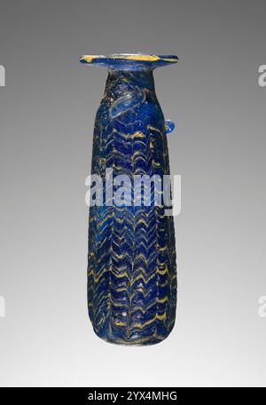 Alabastron, vie-IVe siècle av. J.-C. Flacon de parfum avec motif plume. Informations supplémentaires : alabastron formé à noyau de verre opaque bleu foncé (cobalt) avec de fines bandes de jaune opaque traînées autour de la pièce horizontalement puis verticalement peignées pour former un motif aminci. Une poignée à oreilles survit. Banque D'Images
