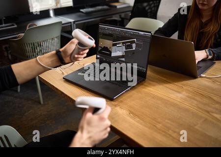 Une installation pour les jeux de réalité virtuelle comprenant un ordinateur portable et des contrôleurs sur un bureau en bois dans un concept d'environnement d'espace de travail technologique Banque D'Images