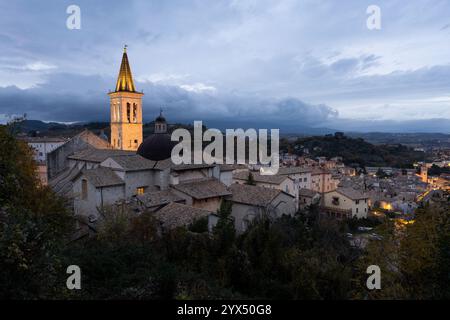 Vue panoramique en soirée sur la vieille ville de Spoleto en Ombrie, Italie. Le soufflet illuminé de la cathédrale surplombe d'anciens toits en tuiles. Banque D'Images