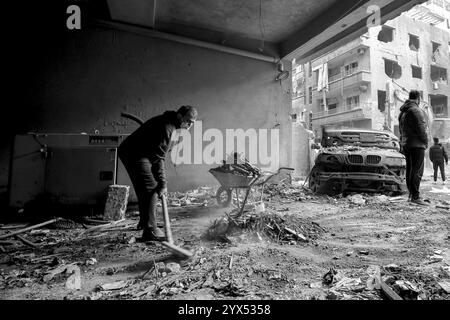 Beyrouth, Beyrouth, Liban. 13 décembre 2024. Un Libanais nettoie les débris de l'entrée d'un bâtiment dans le quartier dévasté de Basta qui a été touché par des raids aériens pendant les deux mois de guerre totale entre Israël et les militants du Hezbollah. Les habitants de la région ont élevé la voix demandant au gouvernement de dédommager des dizaines de bâtiments dévastés et de trouver des abris pour les familles qui ont perdu leur maison. (Crédit image : © Marwan Naamani/ZUMA Press Wire) USAGE ÉDITORIAL SEULEMENT! Non destiné à UN USAGE commercial ! Banque D'Images