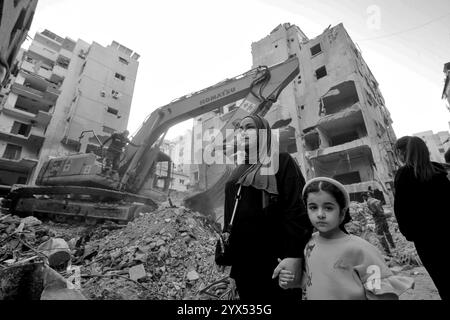 Beyrouth, Beyrouth, Liban. 13 décembre 2024. Une libanaise marche avec sa fille devant un bâtiment détruit lors de raids aériens dans la région de Basta, au fond de Beyrouth, pendant les deux mois de guerre totale entre Israël et les militants du Hezbollah. Les habitants du quartier dévasté de Basta ont élevé la voix demandant au gouvernement de dédommager des dizaines de bâtiments dévastés et de trouver des abris pour les familles qui ont perdu leur maison. (Crédit image : © Marwan Naamani/ZUMA Press Wire) USAGE ÉDITORIAL SEULEMENT! Non destiné à UN USAGE commercial ! Banque D'Images