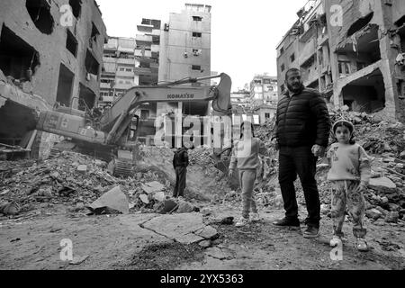 Beyrouth, Beyrouth, Liban. 13 décembre 2024. Un Libanais marche avec ses filles devant un bâtiment détruit lors de raids aériens dans la région de Basta, au fond de Beyrouth, pendant les deux mois de guerre totale entre Israël et les militants du Hezbollah. Les habitants du quartier dévasté de Basta ont élevé la voix demandant au gouvernement de dédommager des dizaines de bâtiments dévastés et de trouver des abris pour les familles qui ont perdu leur maison. (Crédit image : © Marwan Naamani/ZUMA Press Wire) USAGE ÉDITORIAL SEULEMENT! Non destiné à UN USAGE commercial ! Banque D'Images