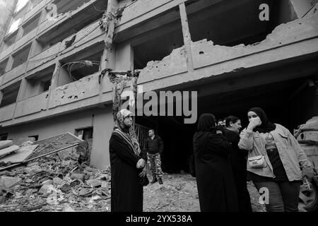 Beyrouth, Beyrouth, Liban. 13 décembre 2024. Les résidents libanais du quartier dévasté de Basta qui a été touché par des raids aériens pendant les deux mois de guerre totale entre Israël et les militants du Hezbollah se tiennent devant un bâtiment détruit. Les habitants de la région ont élevé la voix demandant au gouvernement de dédommager des dizaines de bâtiments dévastés et de trouver des abris pour les familles qui ont perdu leur maison. (Crédit image : © Marwan Naamani/ZUMA Press Wire) USAGE ÉDITORIAL SEULEMENT! Non destiné à UN USAGE commercial ! Banque D'Images