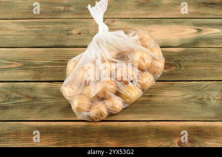 Bébés pommes de terre dans un sac en plastique sur une surface en bois. Copier l'espace. Banque D'Images