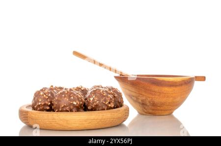 Bonbons au chocolat aux noisettes dans un bol en bois, gros plan, isolé sur fond blanc. Banque D'Images