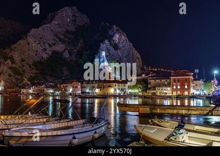 Belle vue nocturne sur la rivière qui coule entre les montagnes rocheuses et sur les rives de la ville il y a de petits bateaux amarrés. Banque D'Images