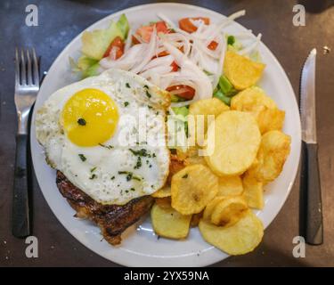 Buenos Aires, Argentine - 22 novembre 2024 : Bife de Chorizo avec un oeuf frit, pomme de terre et salade Banque D'Images