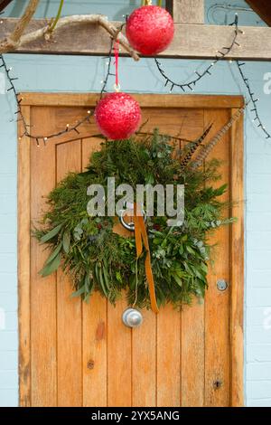 Couronne de Noël traditionnelle faite maison sur une porte d'entrée. Décorations de Noël dans une maison en Angleterre, Royaume-Uni. Banque D'Images