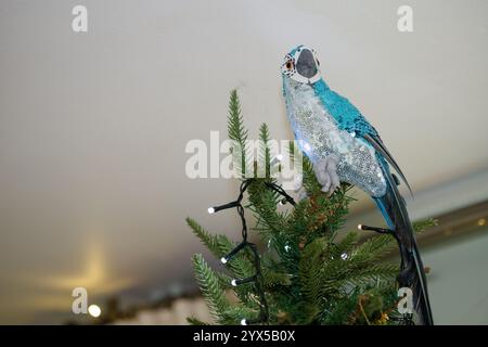 Perroquet au lieu d'une fée au sommet d'un sapin de Noël. Décorations de Noël dans une maison en Angleterre, Royaume-Uni. Banque D'Images