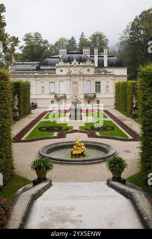 Vue en angle élevé du parterre avec bordures et fontaine d'eau bordée de haies d'arbres feuillus dans le jardin formel du palais Linderhof à la fin de l'été. Banque D'Images