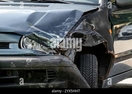 Détail du phare cassé et du pare-chocs sur la voiture sombre après un accident de la circulation Banque D'Images