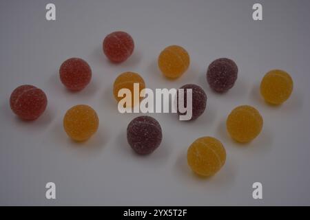 Bonbons finlandais de gelée originaux sous forme de boules rondes recouvertes de sucre blanc. Les bonbons jaunes, oranges, cerises, rouges sont sur un plastique blanc. Banque D'Images