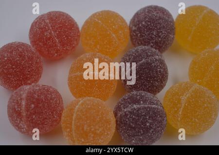 Bonbons finlandais de gelée originaux sous forme de boules rondes recouvertes de sucre blanc. Les bonbons jaunes, oranges, cerises, rouges sont sur un plastique blanc. Banque D'Images
