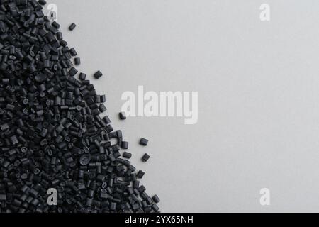 Pile de granulés de plastique noir sur fond gris, vue de dessus. Espace pour le texte Banque D'Images