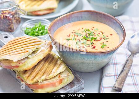 Soupe à la crème de poivrons rouges dans un bol, servie avec panini de dinde grillée, horizontale Banque D'Images