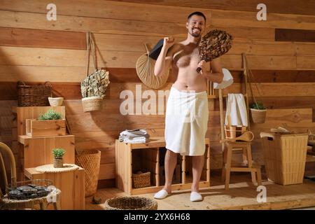 Bel homme avec chapeau en feutre et fouet dans le sauna Banque D'Images