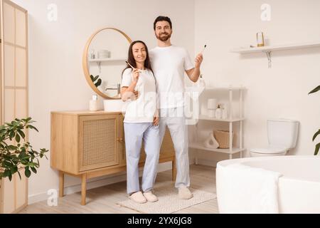 Couple aimant avec brosses à dents serrées dans la salle de bains Banque D'Images