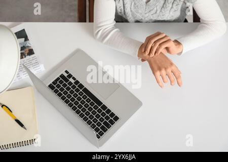 Jeune femme souffrant de douleur au poignet au bureau, vue de dessus Banque D'Images