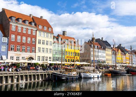 Scène de divertissement et de restaurants à Copenhague à côté du canal dans le quartier de Nyhavn avec des bateaux à voile traditionnels en bois amarrés sur le canal Banque D'Images