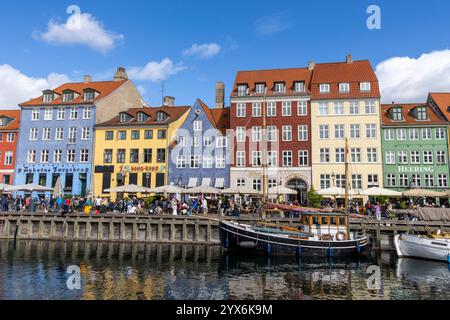 Scène de divertissement et de restaurants à Copenhague à côté du canal dans le quartier de Nyhavn avec des bateaux à voile traditionnels en bois amarrés sur le canal Banque D'Images
