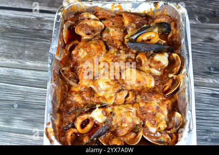 Assortiment de fruits de mer cuisinés au four : filet de poisson, crevettes, calmars, œufs de calmars, œufs de poisson, œufs de poisson, moules, palourdes et crabes avec sauce rouge et herbes, cuites i Banque D'Images