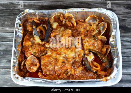 Assortiment de fruits de mer cuisinés au four : filet de poisson, crevettes, calmars, œufs de calmars, œufs de poisson, œufs de poisson, moules, palourdes et crabes avec sauce rouge et herbes, cuites i Banque D'Images