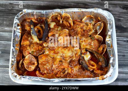 Assortiment de fruits de mer cuisinés au four : filet de poisson, crevettes, calmars, œufs de calmars, œufs de poisson, œufs de poisson, moules, palourdes et crabes avec sauce rouge et herbes, cuites i Banque D'Images