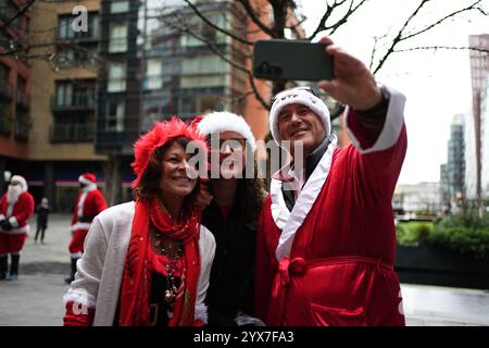 Les gens se sont habillés en Père Noël avant de participer au défilé de Noël Santacon de Londres au Floating Pocket Park à Londres. Date de la photo : samedi 14 décembre 2024. Banque D'Images