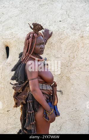 Femme Himba mariée appuyée contre une cabane de boue traditionnelle, le matin, village traditionnel Himba, Kaokoveld, Kunene, Namibie, Afrique Banque D'Images